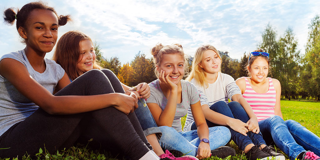 young girls smiling and sitting in a field