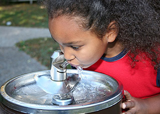 Little girl drinking from a water fountain