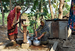 women pumping water from a well