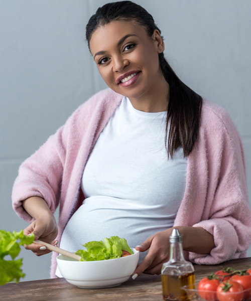 pregnant woman standing and eating a salad