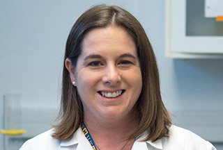 Dana Dolinoy, Ph.D., in a white lab coat