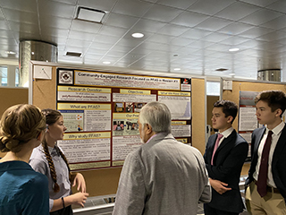 students presenting research on large poster