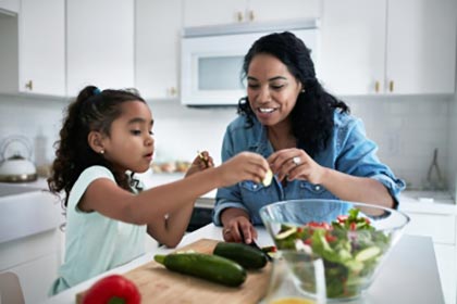parent and child preparing vegetables at home 