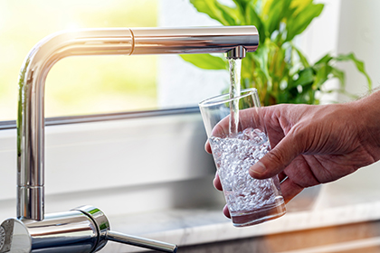 hand holding a glass of water as it fills from a faucet 