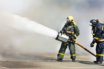 Firemen extinguish a fire with foam within the smoke 