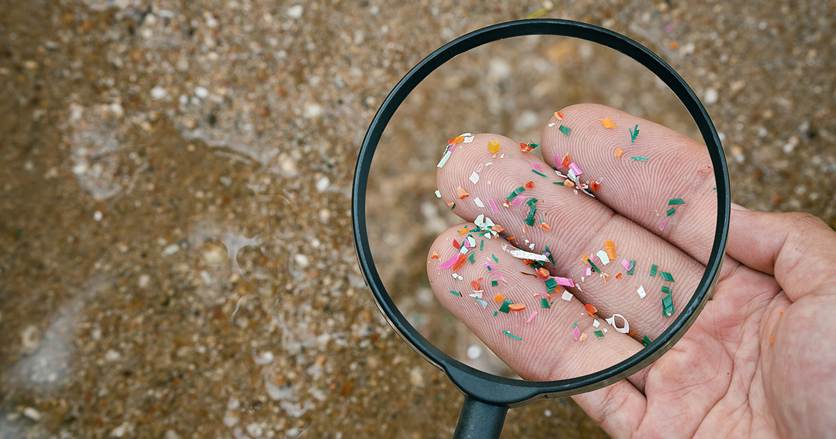 Magnifying glass be using to view microplastics in one's hand