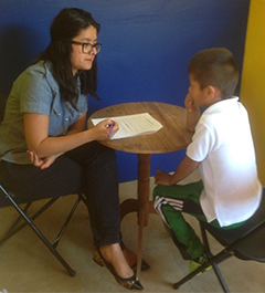Liliana Aguayo, Ph.D. at a desk with a little boy