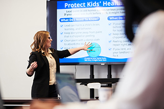 Abby Mutic presenting at a large screen projector