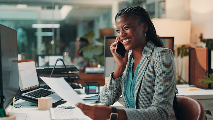african-american woma sitting at a desk in an office, talking on the phone