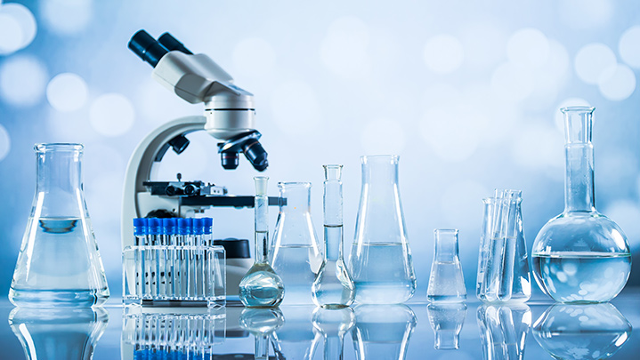 microscope surrounded by beakers