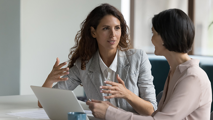 two women sitting before a laptop discussing business