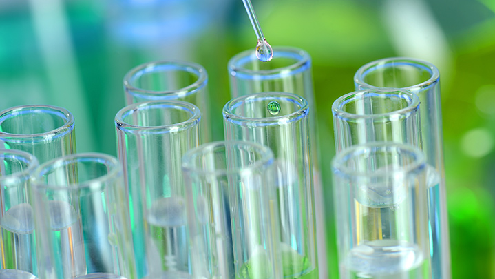 a dropper putting drops into a group of test tubes