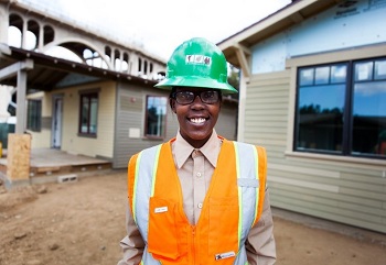 Woman wearing a green hard hat and an orange vest
