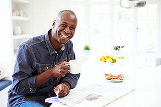Man smiles for photo while holding coffee mug