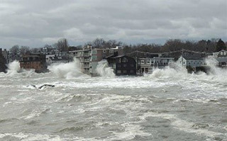 Waves crash against buildings on the shore