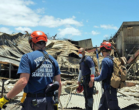 Firefighters standing in front of a damaged building