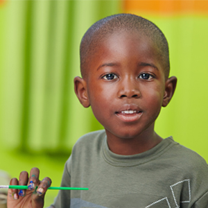 boy holding a paintbrush, looking at us