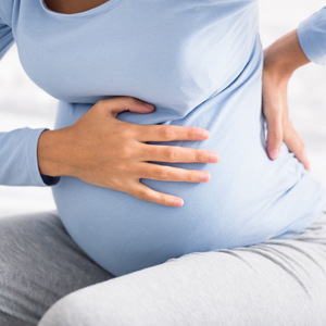 seated pregnant woman holding her belly and back