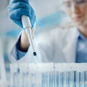 hand holding pipette with a woman's face in background