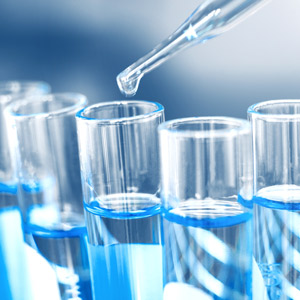 Dropping sample into test tube with light blue liquid.