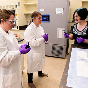 Huei-Chen Lee, Ph.D., right, explains pipetting, which is a technique used to measure and transfer liquids, to Chelsea Andrews, of Coastal Christian High School, Wilmington, and Ashley Haithcock, of Uwharrie Charter Academy, Asheboro.