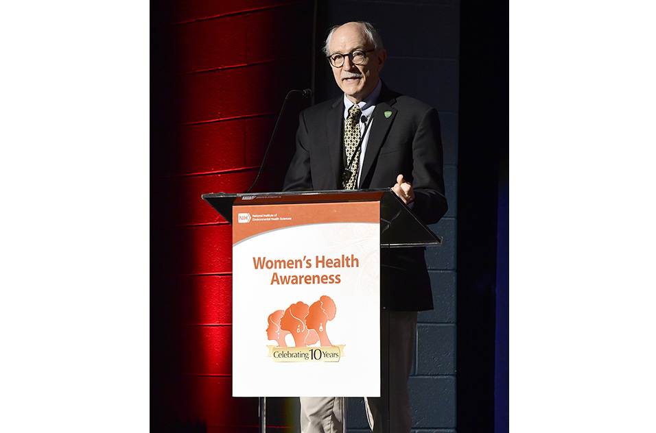 NIEHS and the National Toxicology Program Director Rick Woychik, Ph.D., greets crowd from behind a podium with a WHA sign.