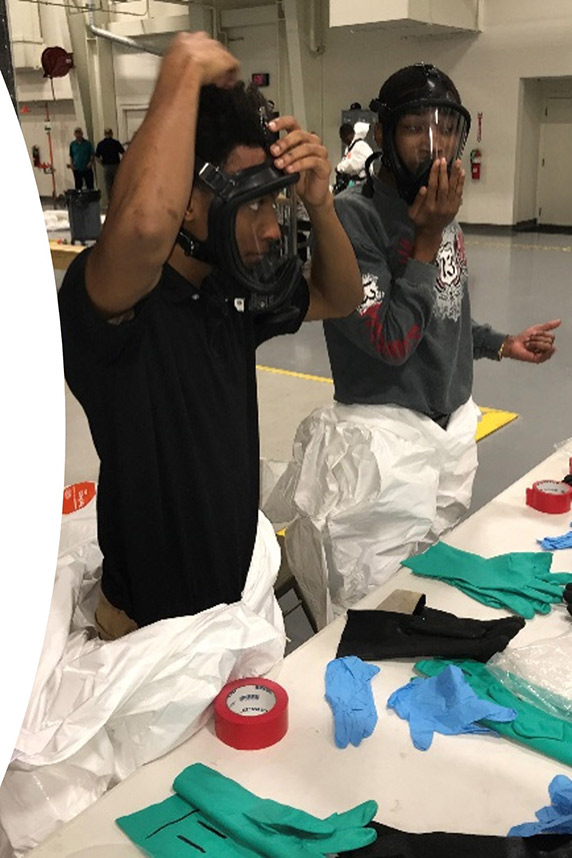 Two workers trying on gas masks during safety training