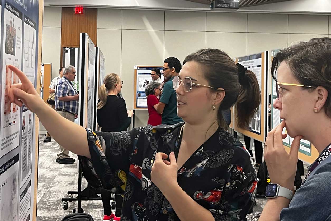 Eva Marques, Ph.D., left, a visiting fellow in the Predictive Toxicology Branch, discusses her work on urban heat exposure. (Photo courtesy of Amy Wang / NIEHS)