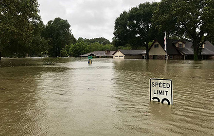 homes and street sign submerged in flood waters