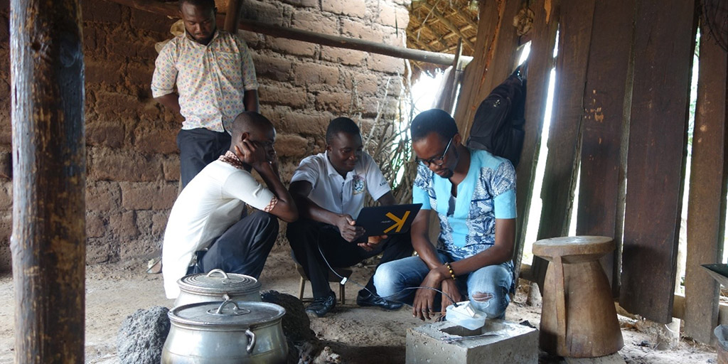 men gathered around a kettle on a fire pit in an open-air structure