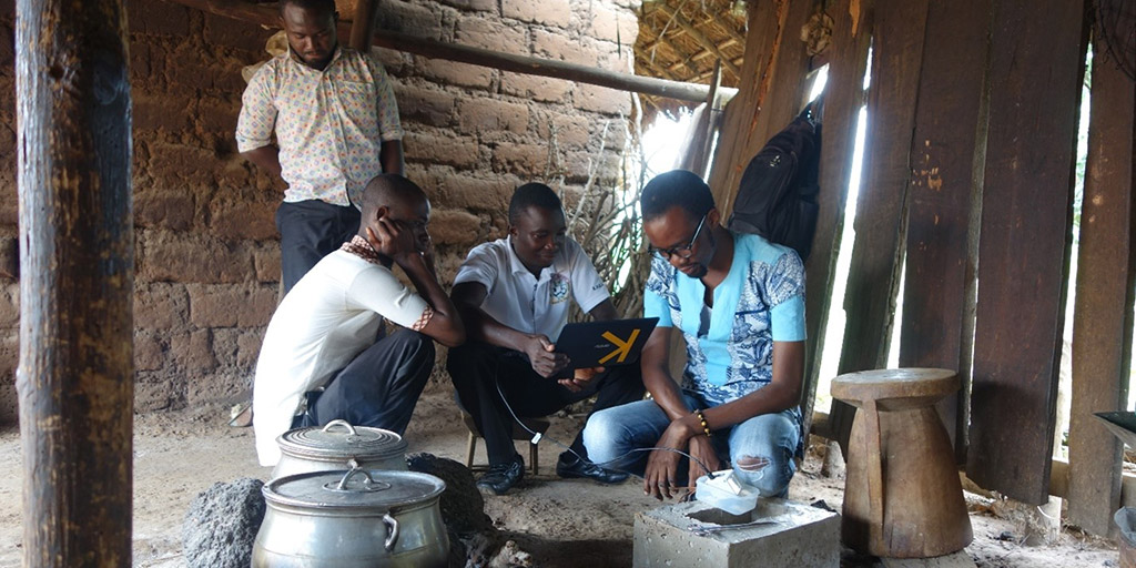 men gathered around a kettle on a fire pit in an open-air structure