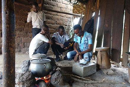 men gathered around a kettle and fire pit in an open-air building