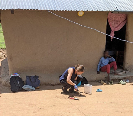 Mariah Coley, Ph.D. mixing soil samples in a container in front of a home with a child watching