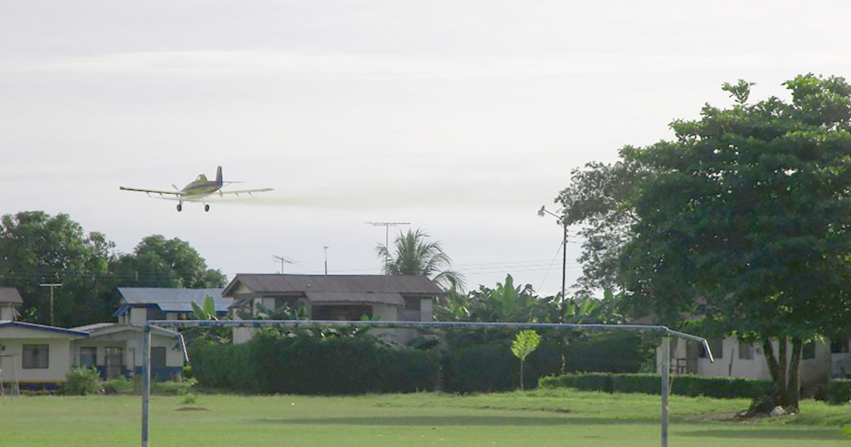 small airplane releasing pesticides near homes