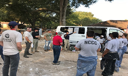 group of volunteers gathered around a van and listening to instructions