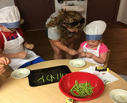 Woman and two children in chef hats cooking together