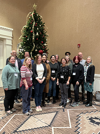 Group photo of Annual Meeting Planning Committee in front of a Christmas tree