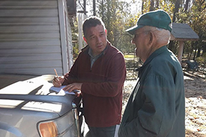 Andrew George standing and outside a house and talking with a man