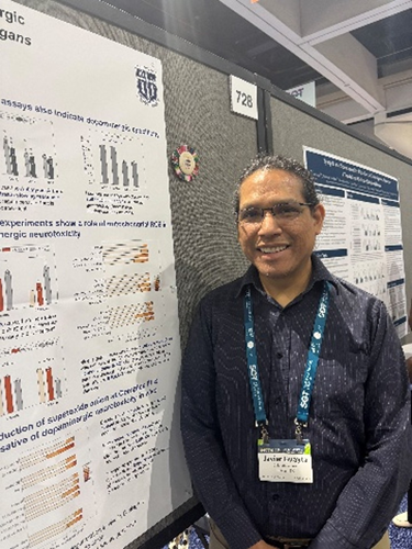 Javier Huayta standing beside his research poster