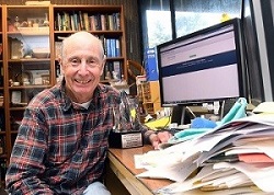 Bruce Hammock sitting at a desk full of papers