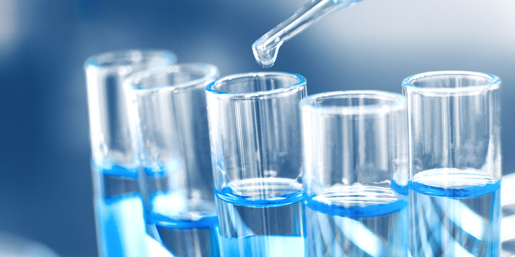 Dropping sample into test tube with light blue liquid.