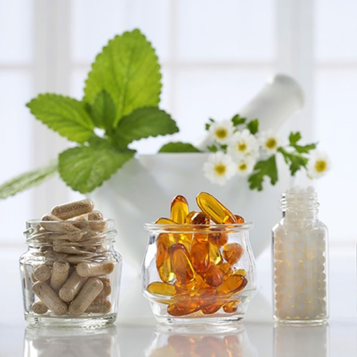 jars of vitamins in front of a bowl of flowers and plants