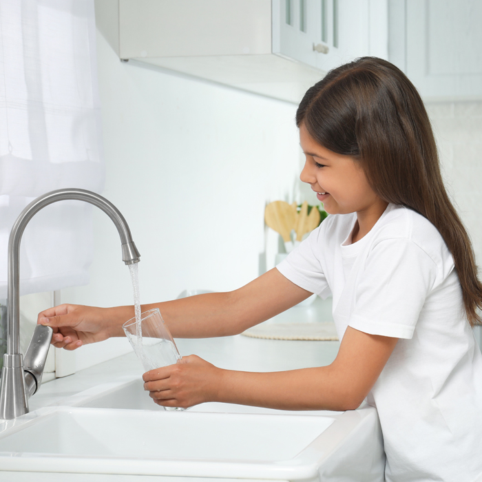 little girl getting water from a faucet