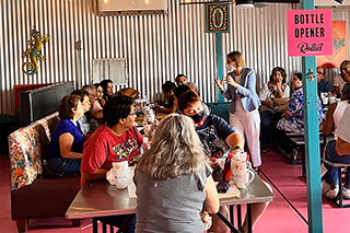 Sweasy (standing, right) explains her research on gene-environment interactions to community members from South Tucson.
