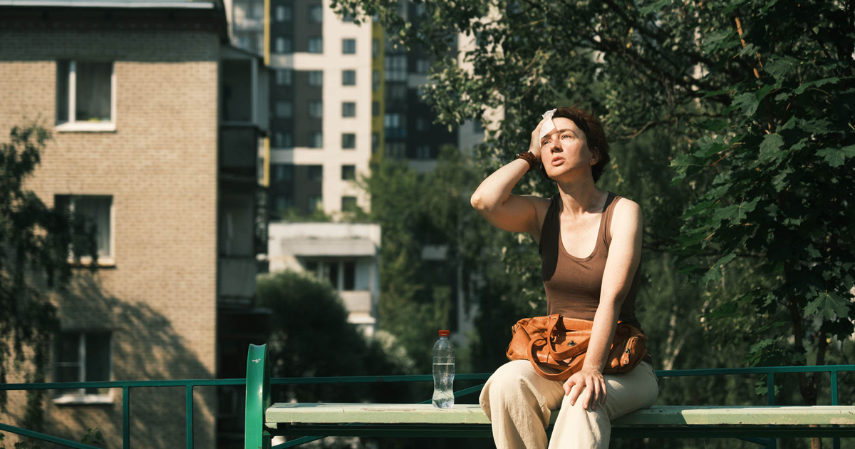 woman sitting in the sun holding her head