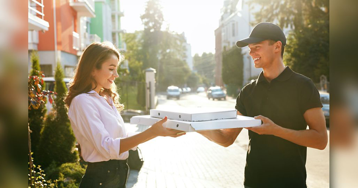 man and woman holding pizza boxes