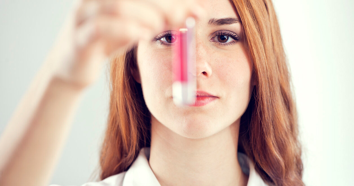 scientist looking at liquid in test tube