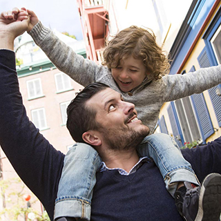 man holding onto child who is sitting on his shoulders
