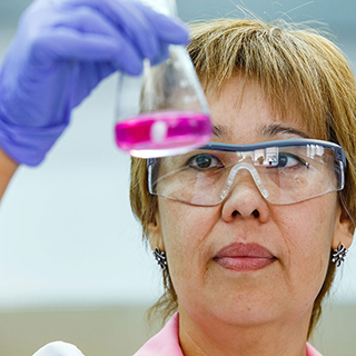woman looking at a vile containing pink liquid