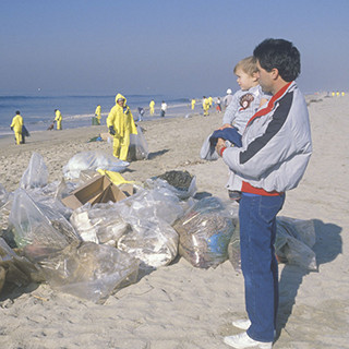 man holding child watching efforts to clean up oil spill